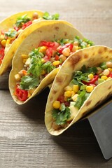 Tasty vegetarian tacos with chickpeas, corn and quinoa served on wooden table, closeup