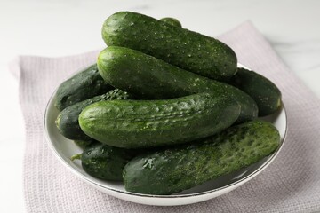 Fresh cucumbers in bowl on white table, closeup