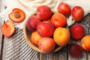 Fresh ripe apricots in bowl on wooden table, flat lay