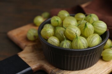 Fresh green gooseberries in bowl on table, closeup. Space for text