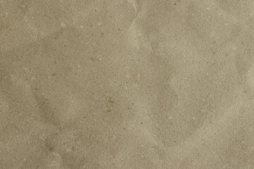 Close-up of a crumpled, light brown kraft paper texture. Its earthy tone