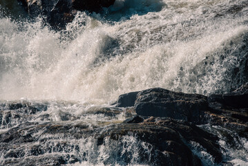 Obraz premium streams of clear waterfall water and stone banks of a mountain river