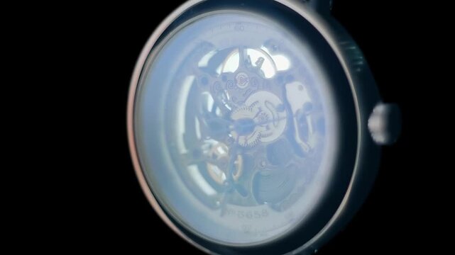 The skeleton watches reflect bright flashes, in tact with the time they accurately count, on a black background, on a black background. Closeup. Macro