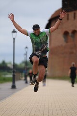 A happy runner jumps during the parkrun sporting event in front of historic castle in  Malbork
