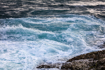 The ocean is rough and choppy, with waves crashing against the rocks