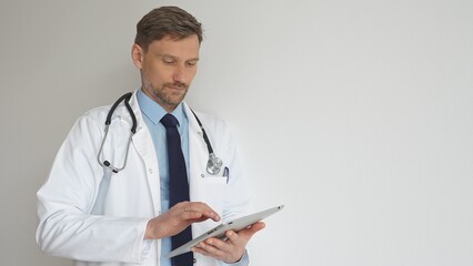 Confident doctor man wearing stethoscope and white coat, standing with crossed arms and gazing thoughtfully, representing medical professionalism and expertise. Medicine and health care