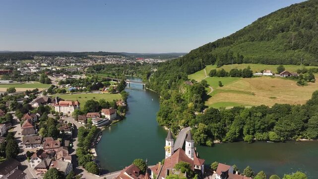 Drone pushes over Aarburg&rsquo;s red‑roof castle and church with bridge over Aare river flowing through historic Swiss old town in Canton Aargau.