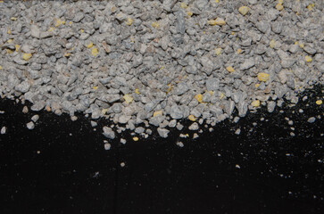 Layer of gray and yellow mineral rock blend on black surface for geological studies and raw...