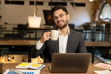 Young caucasian man sitting in the office and having coffee