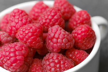 Raspberries in white bowl on black background for fruit dessert or clean eating concept