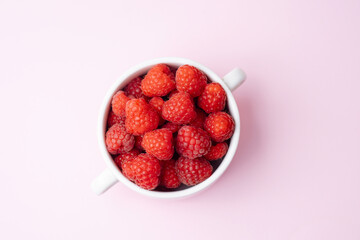 Top view of raspberries in cup on pink background for diet blog or fruit branding concept