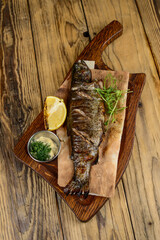 whole fried fish grilled on a wooden board with lemon