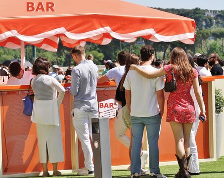 Bar terraza de verano tipo chiringuito con toldo naranja y personas tomando una copa y disfrutando al aire libre de la restauraci&oacute;n junto a naturaleza