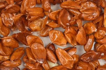 A close-up, full-frame shot of peeled almond skin, showcasing its wrinkled texture and brown color