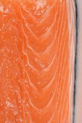 A detailed macro shot of a raw salmon fillet, showcasing the vibrant orange flesh, natural texture, and white lines in the fish