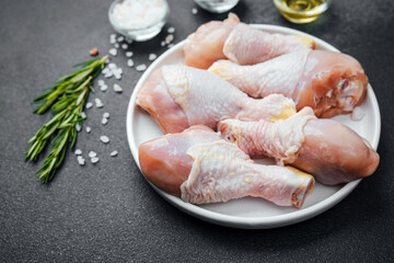 Chicken drumsticks raw with spices and herbs on white plate