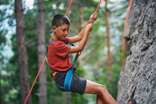 Boy holding climbing rope during rock descent in forest