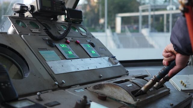 Train driver operating levers and controls in cabin. Clip