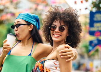 Portrait of two young women girls walking in the city street, drinking coffee and having fun.