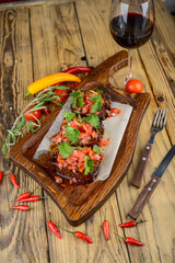 chopped fried ribs with sauce sprinkled with tomatoes and herbs on the background
