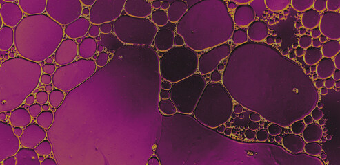 Abstract oil bubbles on vibrant purple background, macro view. Close-up image of oil bubbles forming organic patterns in water, set against a glowing violet and orange backdrop with striking contrast