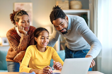 Mother, father and daughter doing homework with laptop at home. Mom, dad and teenage black girl happy using laptop. Teen girl and parents sitting at home working with notebook