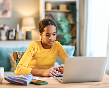 Portrait of a teenage girl having fun using laptop or doing homework with laptop at home