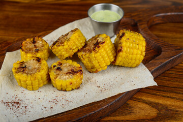 grilled corn in pieces on parchment on a wooden board on a wooden background