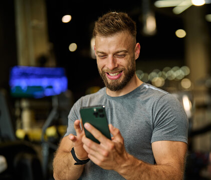 Portrait of a young man using a phone ant exting taking a break exercising in a gym, running using  thereadmill machine equipment, healthy lifestyle and cardio exercise at fitness club concepts