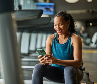 Portrait of a young black woman using a phone ant exting taking a break exercising in a gym, running using  thereadmill machine equipment, healthy lifestyle and cardio exercise at fitness club concept