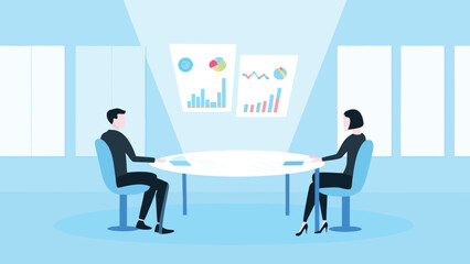 Two people sitting at a table discussing charts and graphs in a bright and modern office space setting