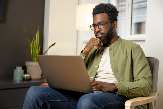 Young dark-skinned man in eyeglasses working and looking thoughtful