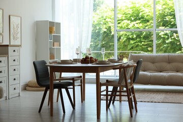 Beautiful table setting, chairs and decor in dining room. Interior design