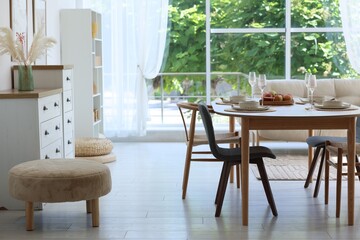 Beautiful table setting, chairs and decor in dining room. Interior design