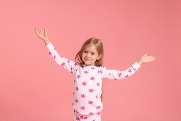 Cute little girl in pajamas on pink background