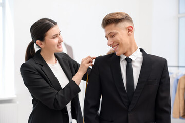 Tailor measuring jacket on man in atelier