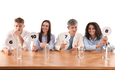 Panel of judges voting with score signs at table on white background