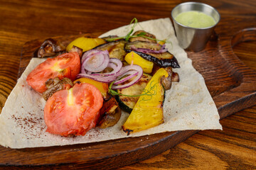 Grilled vegetables on parchment on a wooden board on a background
