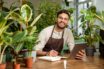 Young man in eyeglasses working in the flower shop and looking busy