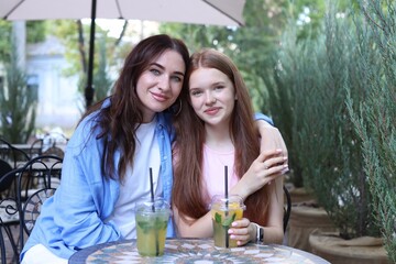 Portrait of beautiful mother and her teenage daughter in outdoor cafe