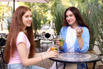 Beautiful mother and her teenage daughter spending time together in outdoor cafe