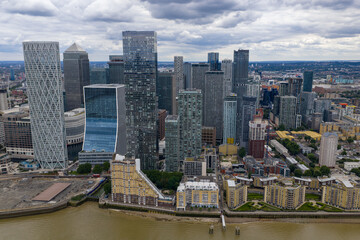 Fototapeta premium Close-up aerial shot of Canary Wharf's dense cluster of towers under cloudy skies.