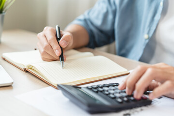 Deduction planning, debt asian accountant hand using calculator to calculating money balance from bill and income, cost budget expenses for pay money form personal individual on table at home.
