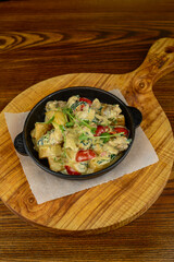 Potato fries with mushrooms and tomatoes in cheese sauce in a pan