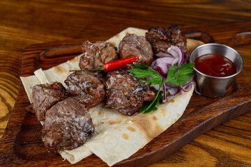 fried beef kebab in pita bread with onions and herbs on a wooden board macro photo