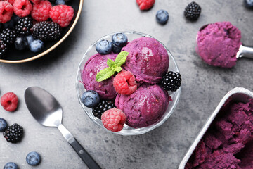 Delicious sorbet with fresh berries and mint in dessert bowl on grey textured table, flat lay