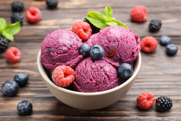 Delicious sorbet with fresh berries and mint in bowl on wooden table, closeup