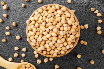chickpeas in bowl on black background with scattered grains for vegan protein, healthy eating or ingredient concept