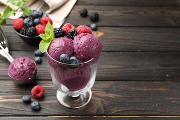 Delicious sorbet with fresh berries and mint on wooden table, closeup. Space for text