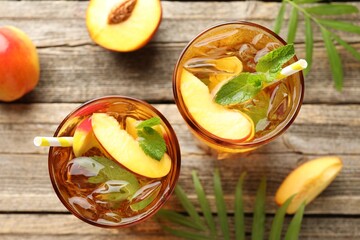 Refreshing iced peach tea in glasses and fresh fruits on wooden table, flat lay